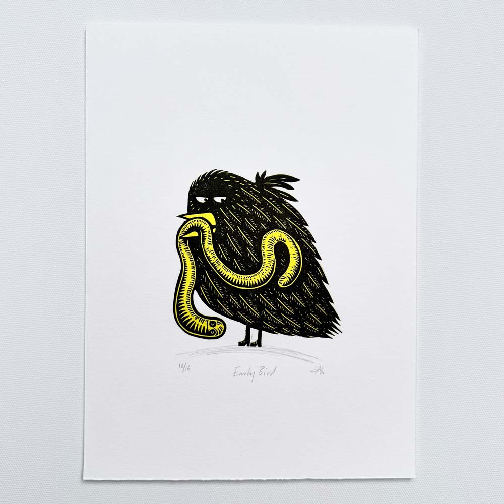 Early Bird handmade linocut print showing a black bird holding a yellow worm by Tigerlino