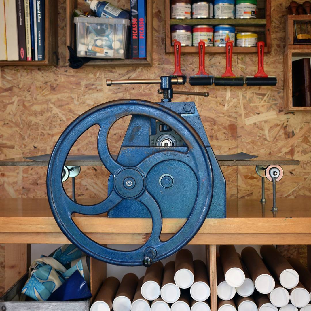 press A blue etching press sat in a studio with skateboards in the background on the wall